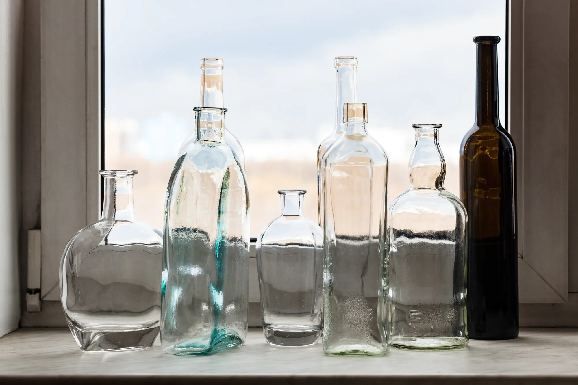 Merxally many-empty-bottles-on-windowsill-and-view-of-park-image